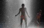 Dos jóvenes disfrutan del refrescante efecto de los surtidores de agua para combatir el calor de Pamplona de este inusual mes de junio
