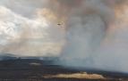 Un helicóptero trabaja en la extinción del incendio producido en Erice de Iza, mientras los vecinos de viviendas cercanas al fuego miran con preocupación el trabajo de los bomberos.