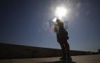 Una mujer se protege del sol con un paraguas mientras pasea por el puente romano de Córdoba