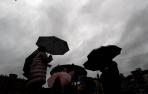 Un grupo de personas se protege con paraguas de la lluvia en Pamplona.
