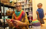 Lluna Barquero tejiendo una bufanda de colores en su nueva tienda.