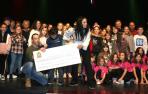 El niño Álex Berdonces y sus padres posan con el cheque y artistas que actuaron en la gala.