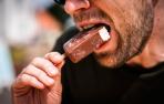 Un hombre come un helado cubierto de chocolate.