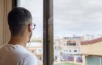 Imagen de un hombre mirando por la ventana