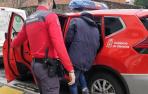 Un policía foral introduce a un detenido en el vehículo policial.