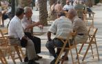 Un grupo de personas mayores conversa en un pequeño corro al aire libre