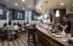 Un camarero del bar La Estrella sirve bebidas en el interior del local con varios clientes sentados.