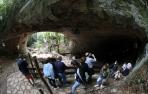Un grupo de visitantes se detiene a contemplar la cueva de Zugarramurdi en un periplo por su núcleo urbano.