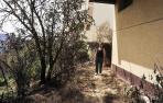 Mª Jesús Janices Valencia, en la parte trasera de su vivienda, con el suelo ennegrecido y la vegetación, sus plantas y flores quemadas. Consiguieron apagar el fuego antes de que alcanzase la fachada