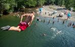 Un joven se lanza al río Arga desde el puente de Irotz, lugar de refresco para muchas personas en esta ola de calor