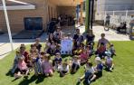Alumnado y profesorado de la escuela infantil 0-3 años de Aoiz, con el cartel anunciador de las fiestas