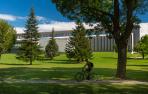 Un estudiante circula por el campus de la Universidad de Navarra con el edificio Amigos al fondo