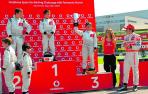 Mikel Azcona levanta la copa y recibe los aplausos de Fernando Alonso, a su derecha.