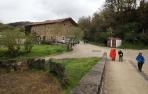 Varios peregrinos se disponen a cruzar el Puente de la Rabia de Zubiri. Al fondo, la conocida como Casa Apolonia, donde se proyecta la casa de cultura que dará servicio a todo el valle de Esteribar.