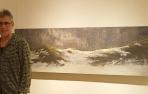 El artista riojano Juan José Ortega, junto a uno de los paisajes nevados que forman parte de la exposición que presenta en Pamplona