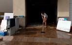 Una mujer limpia su vivienda tras las lluvias en Tarragona