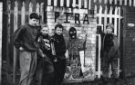 Niños posan junto a un mural callejero en honor a los miembros del IRA Provisional (PIRA), un grupo armado escindido del IRA, en Belfast