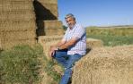 Roberto Francés Clemos, sentado en unas pacas de paja en su almacén de Fontellas