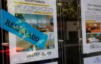 Anuncio de de un piso en en venta con el cartel de reservado en el escaparate de una inmobilaria