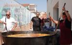 El concejal Joaquín Bermejo mira al reloj, mientras la cocinera se afana con la paella