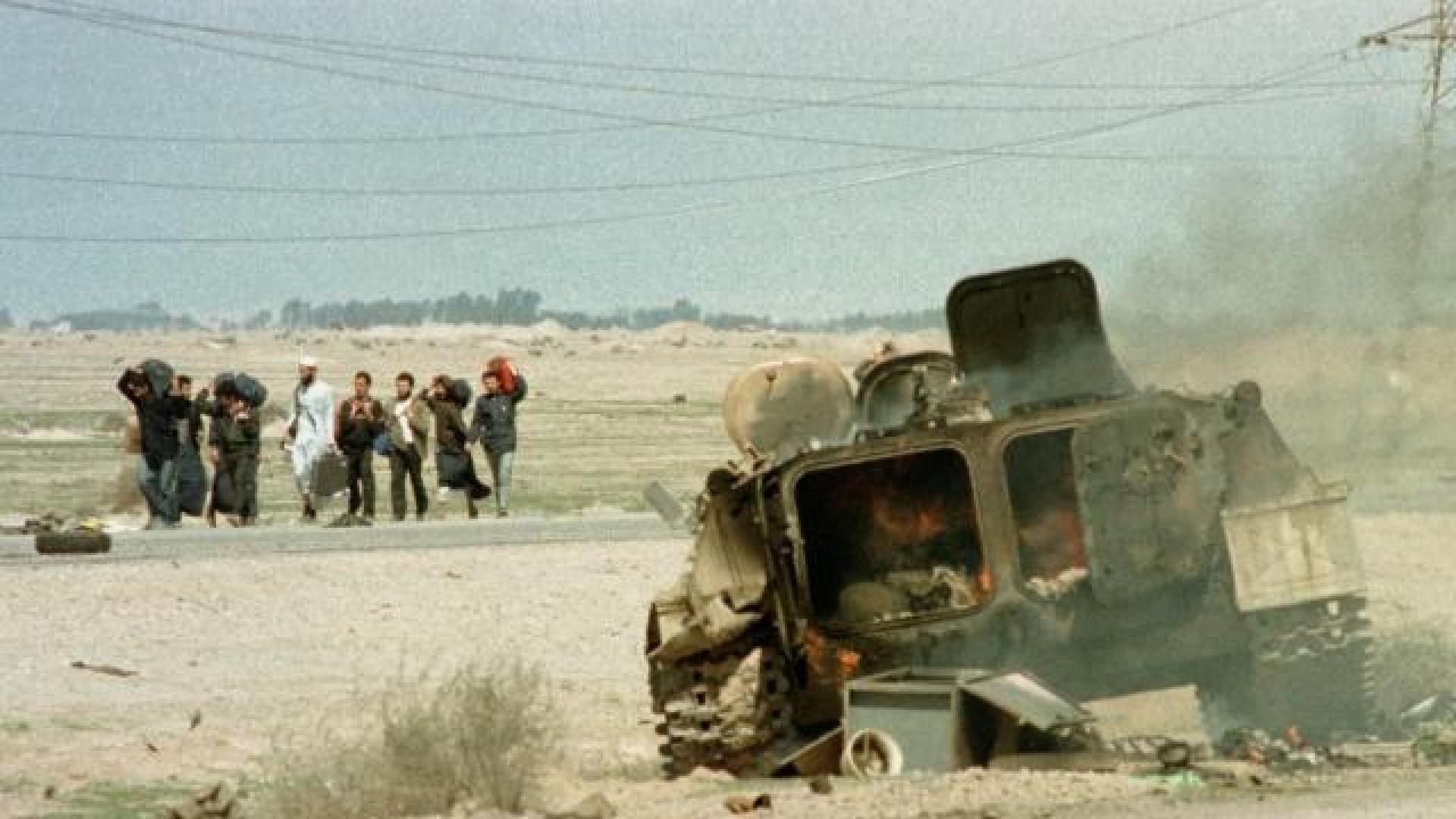 Un grupo de refugiados kuwaities pasa junto a un blindado destrozado en la carretera de Basora, días después del final de la Guerra del Golfo de 1991. 	REUTERS