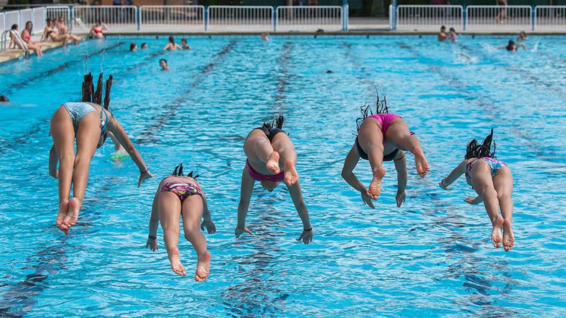 Un grupo de niñas saltando a una piscina.