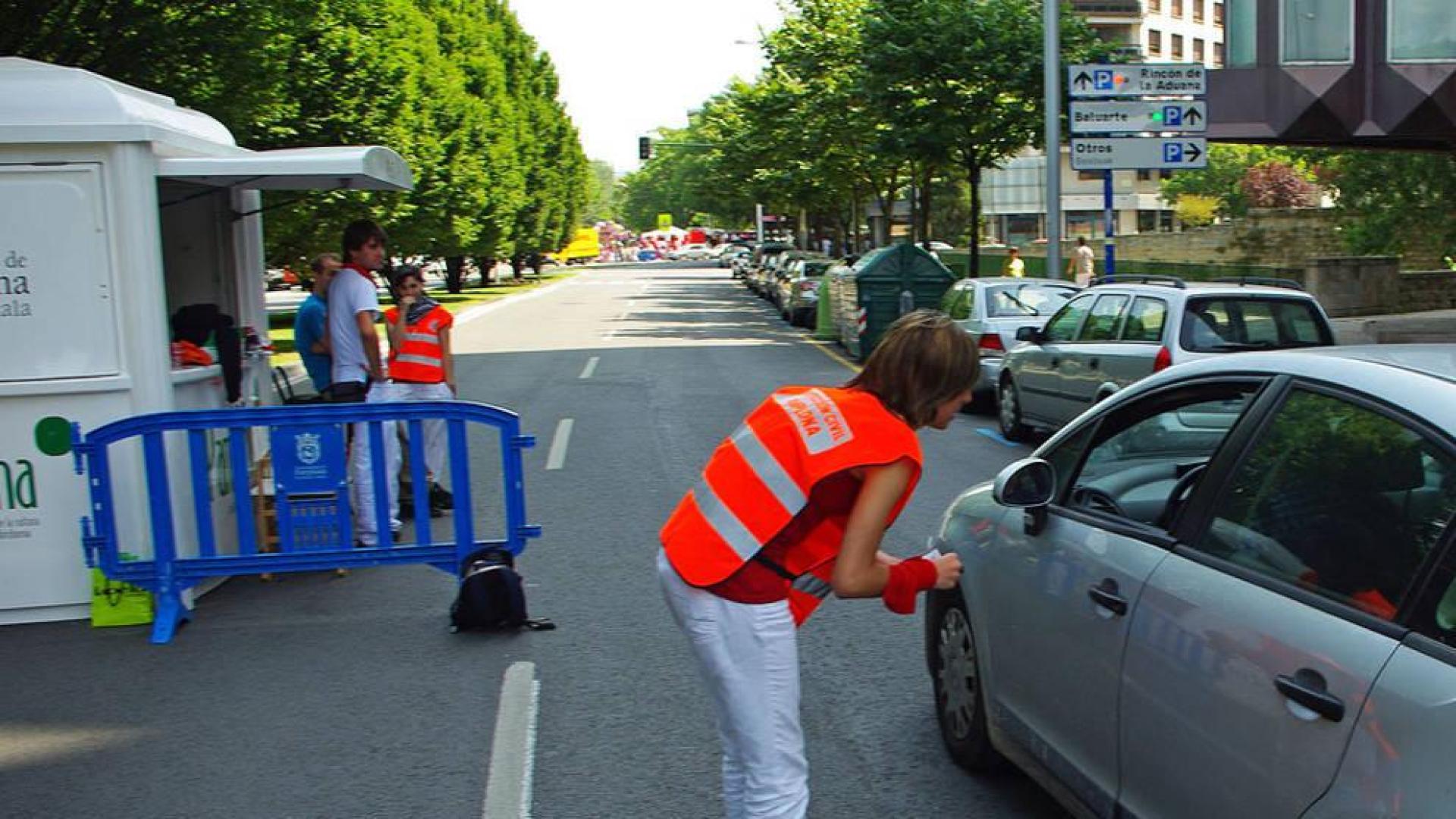 Una joven 'naranjito' da indicaciones a un conductor durante las fiestas de San Fermín de 2010.