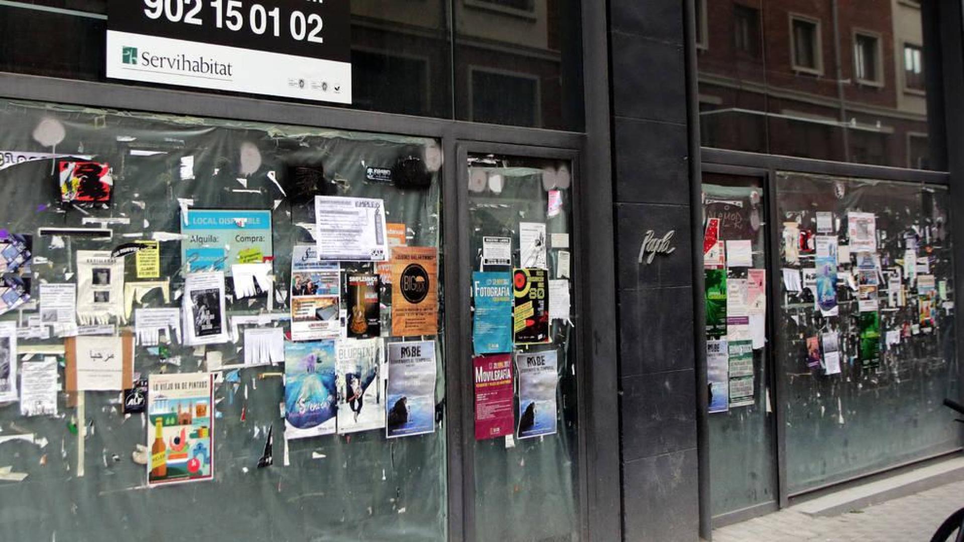 Decenas de carteles publicitarios llenan el escaparate de un local comercial de la calle Bergamín.