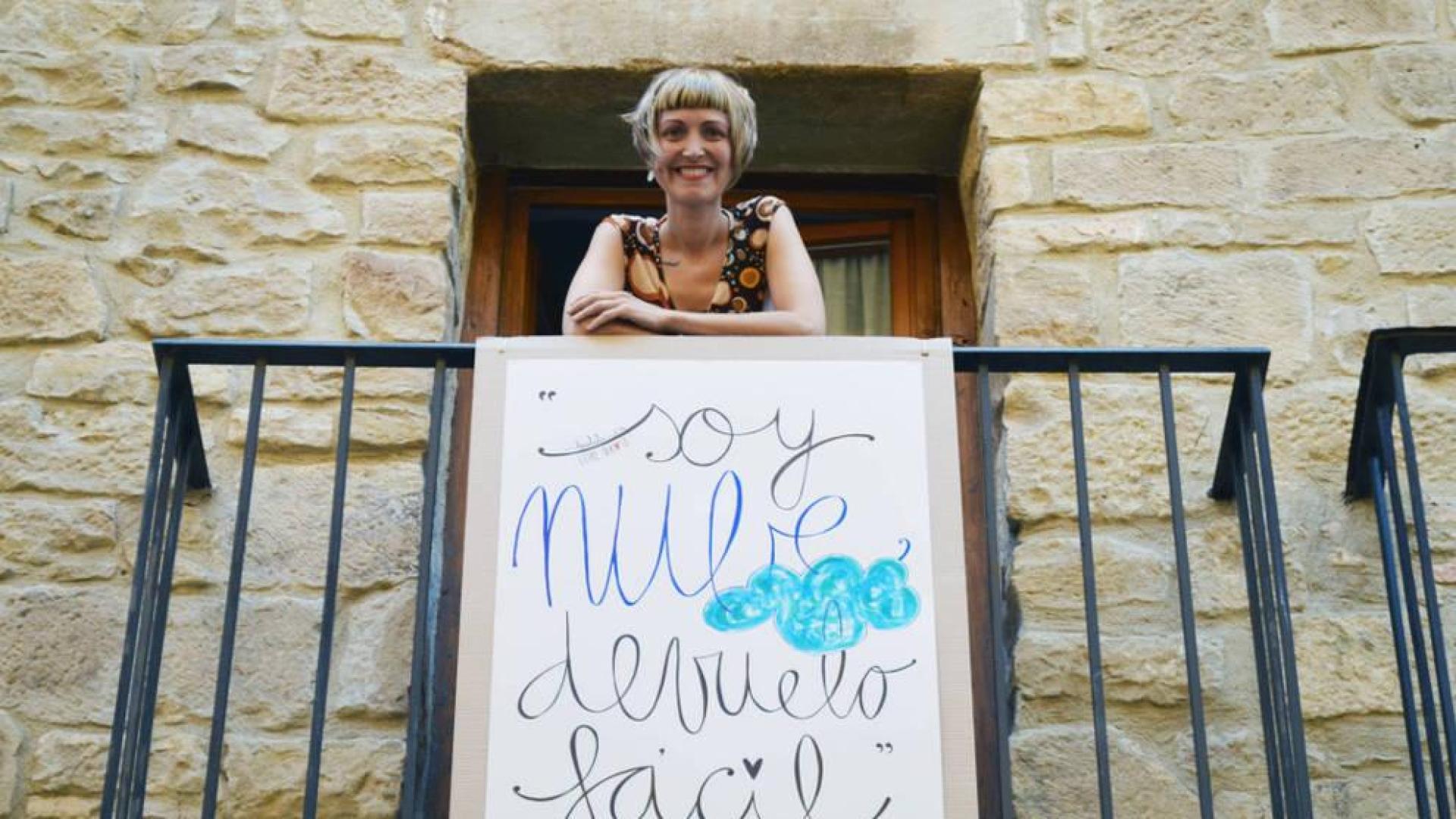 Leire Olkotz, posando en un balcón de Tafalla con el verso de uno de sus poemas en un cartel, como quiere hacer en Pamplona para San Fermín.