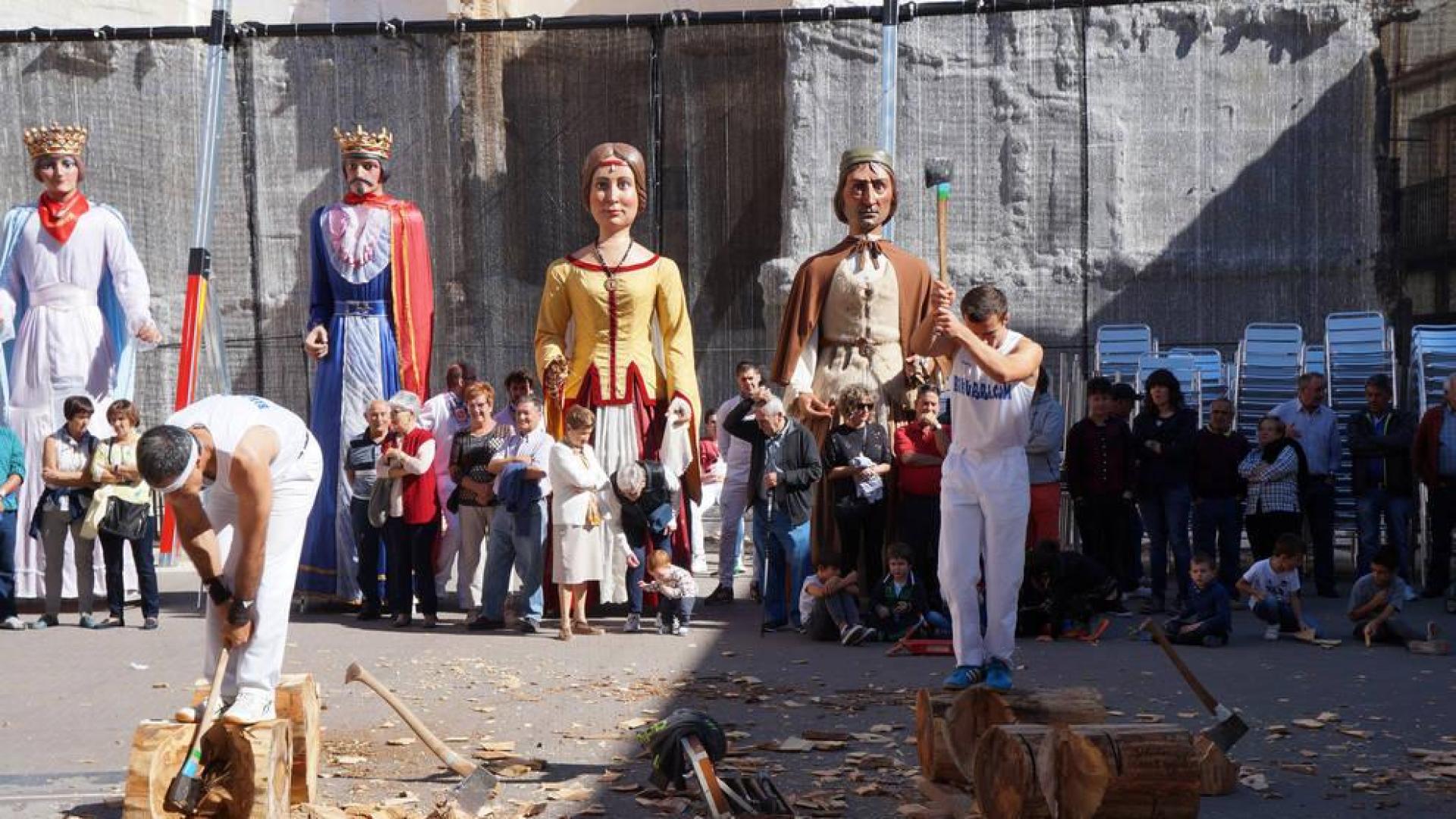 Dos aizkolaris, durante la exhibición de deporte rural y con los gigantes al fondo.