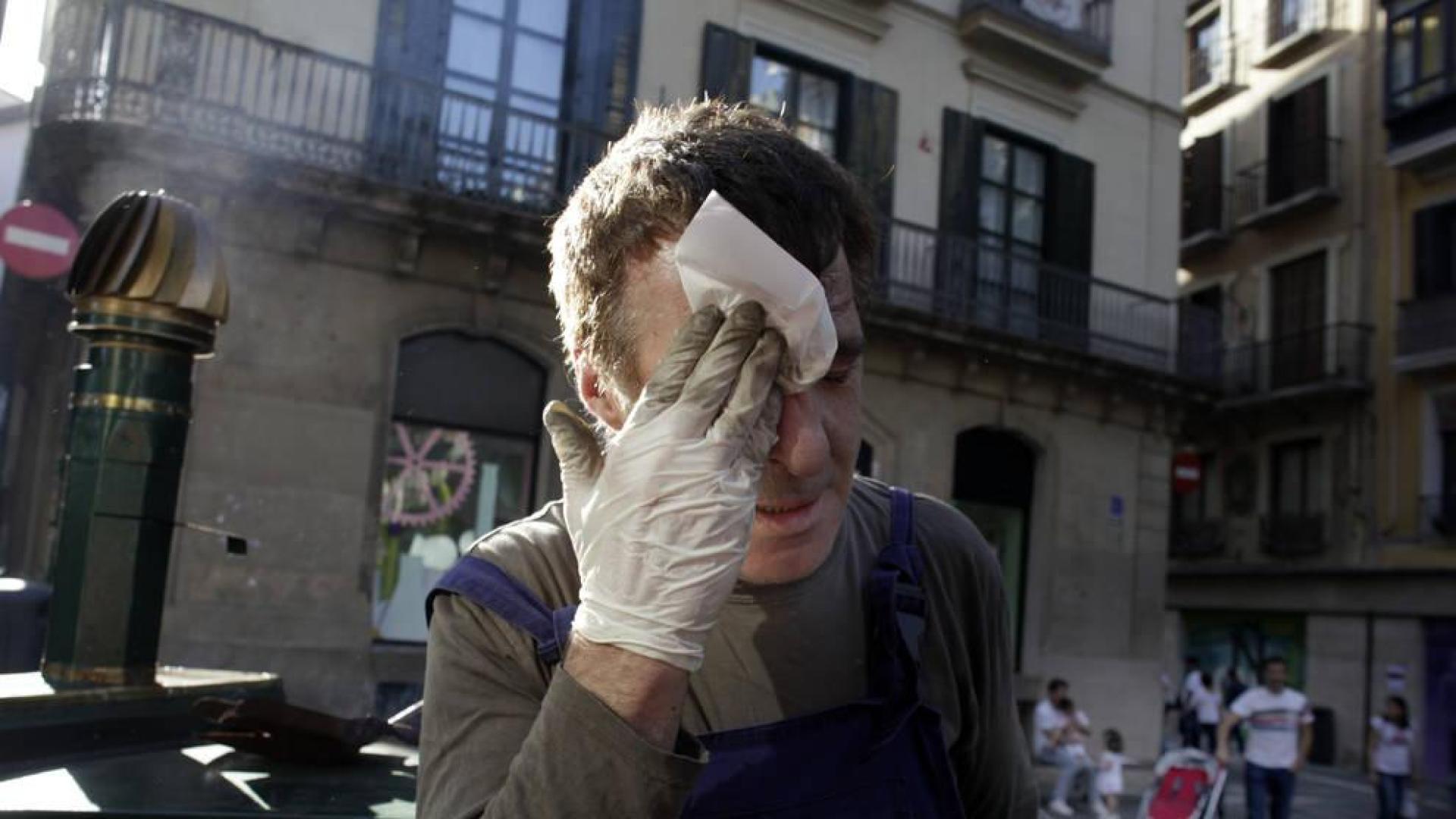 Harold, el castañero de la calle Mercaderes de Pamplona, se retira el sudor de la cara tras prender el carbón de la máquina.