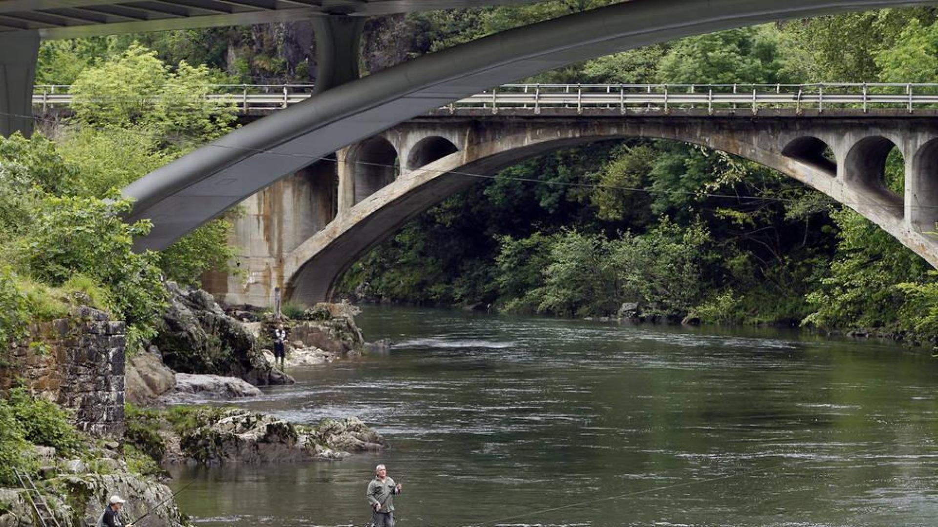 Bajo los puentes de Endarlatsa, dos aficionados tientan la suerte con sus cañas en el río Bidasoa.