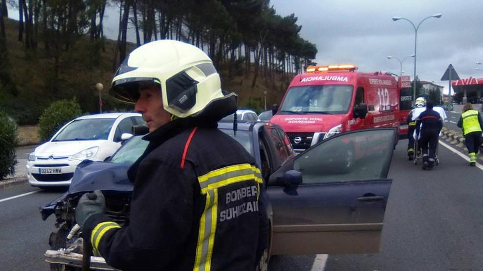 Los bomberos limpian la calzada tras el accidente.