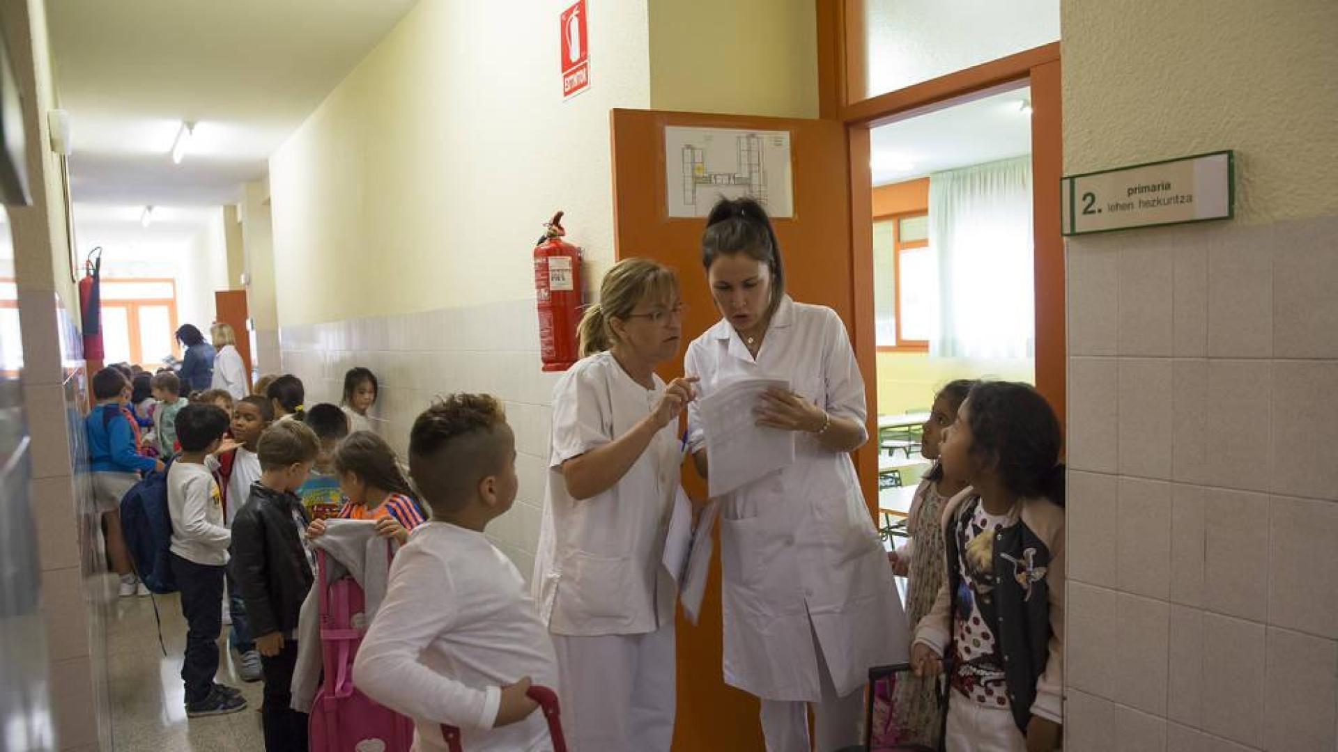 Dos trabajadoras de Ausolan, la principal empresa prestataria del servicio, preparan la entrada al comedor en el Colegio Público Iturrama.