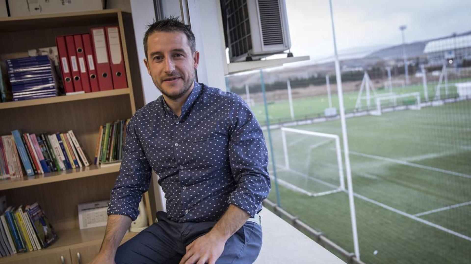 Ángel Alcalde, sentado en el ventanal de su despacho desde el que se puede observar uno de los campos de las instalaciones de Osasuna.
