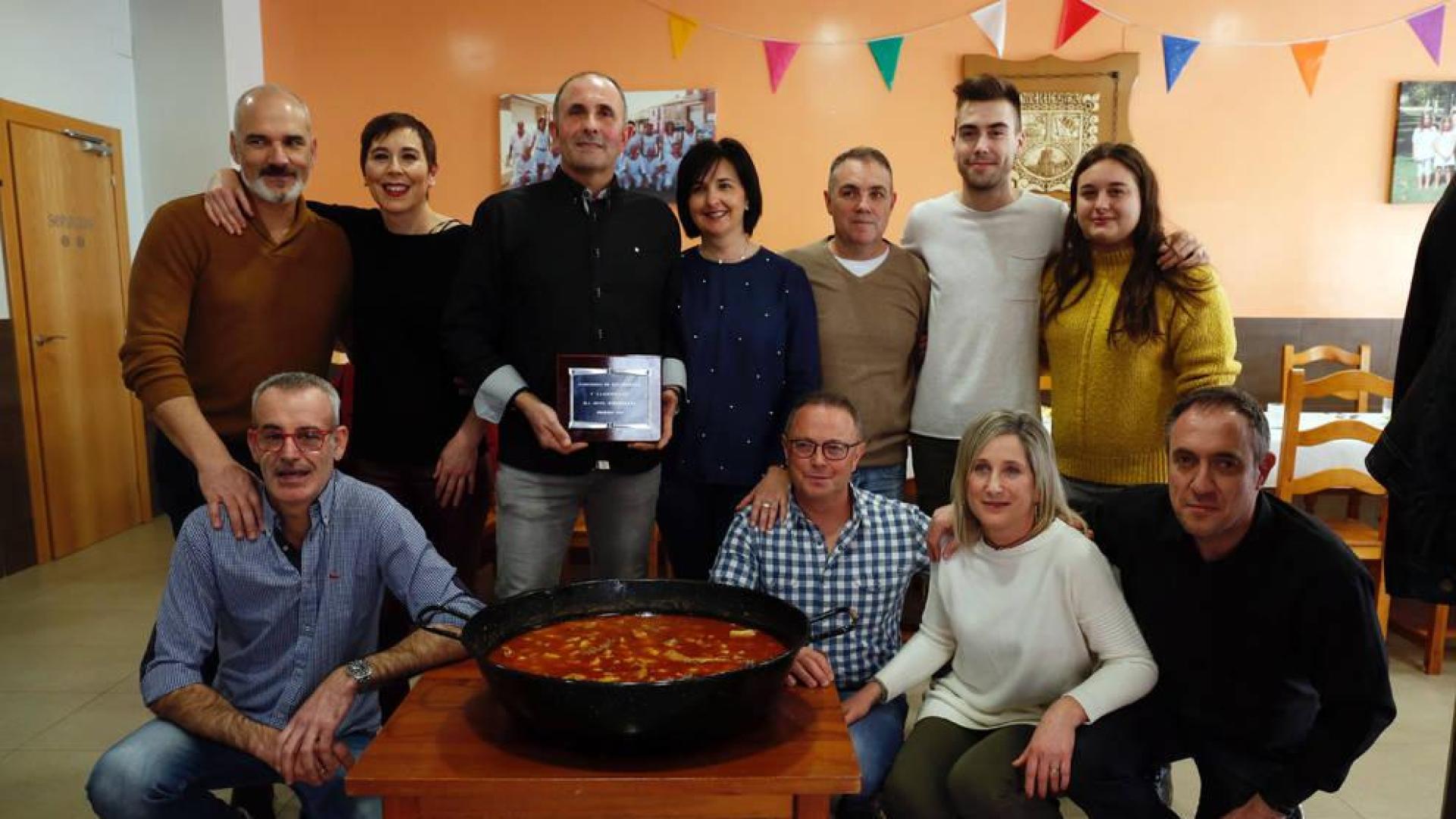 Varios miembros de la peña La Kuesta, con el calderete ganador y la placa conmemorativa.