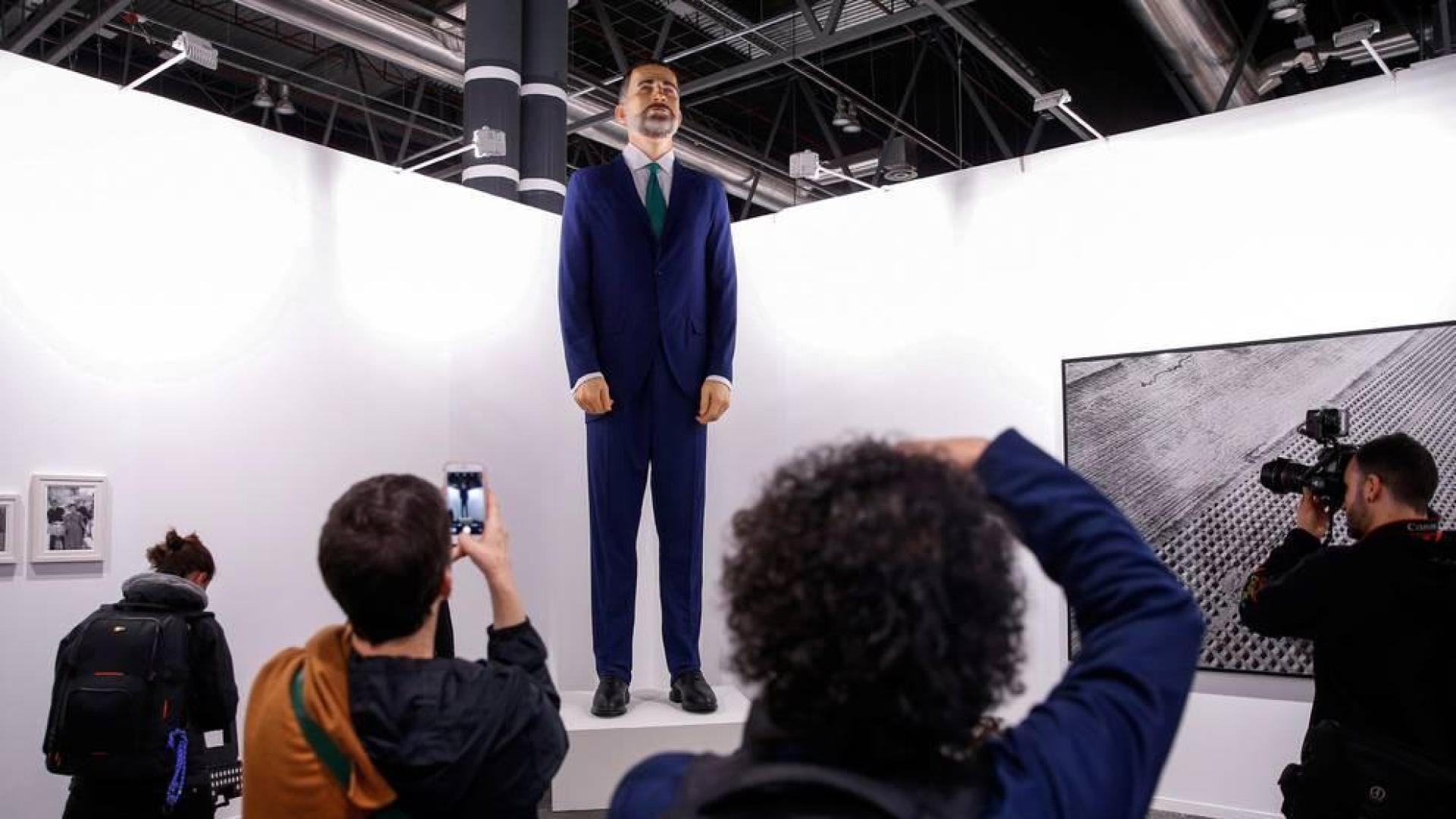 Varias personas observan el "ninot" del rey Felipe VI ,una obra de Santiago Sierra y Enrique Merino, expuesta en ARCO 2019.