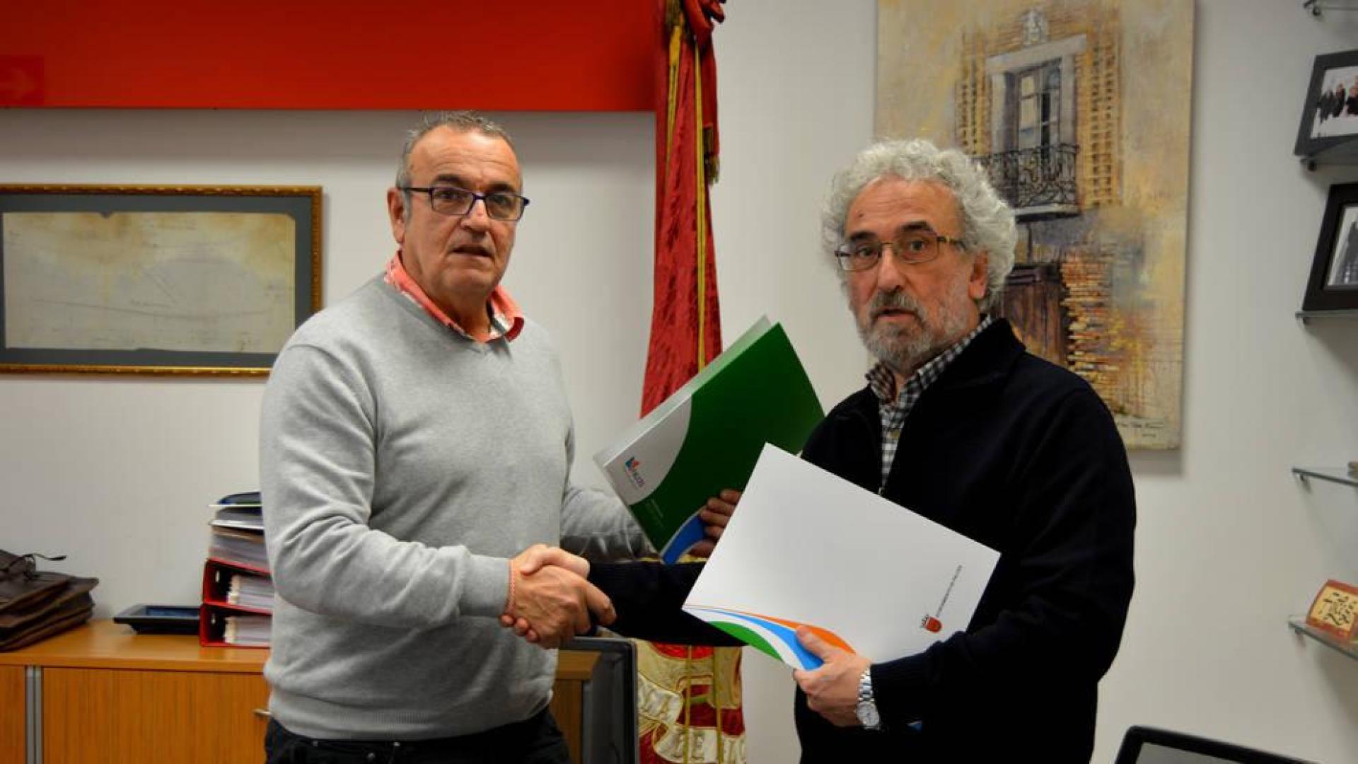 Valentín García (izda.) y Francisco Soto se dan la mano tras haber firmado el convenio.