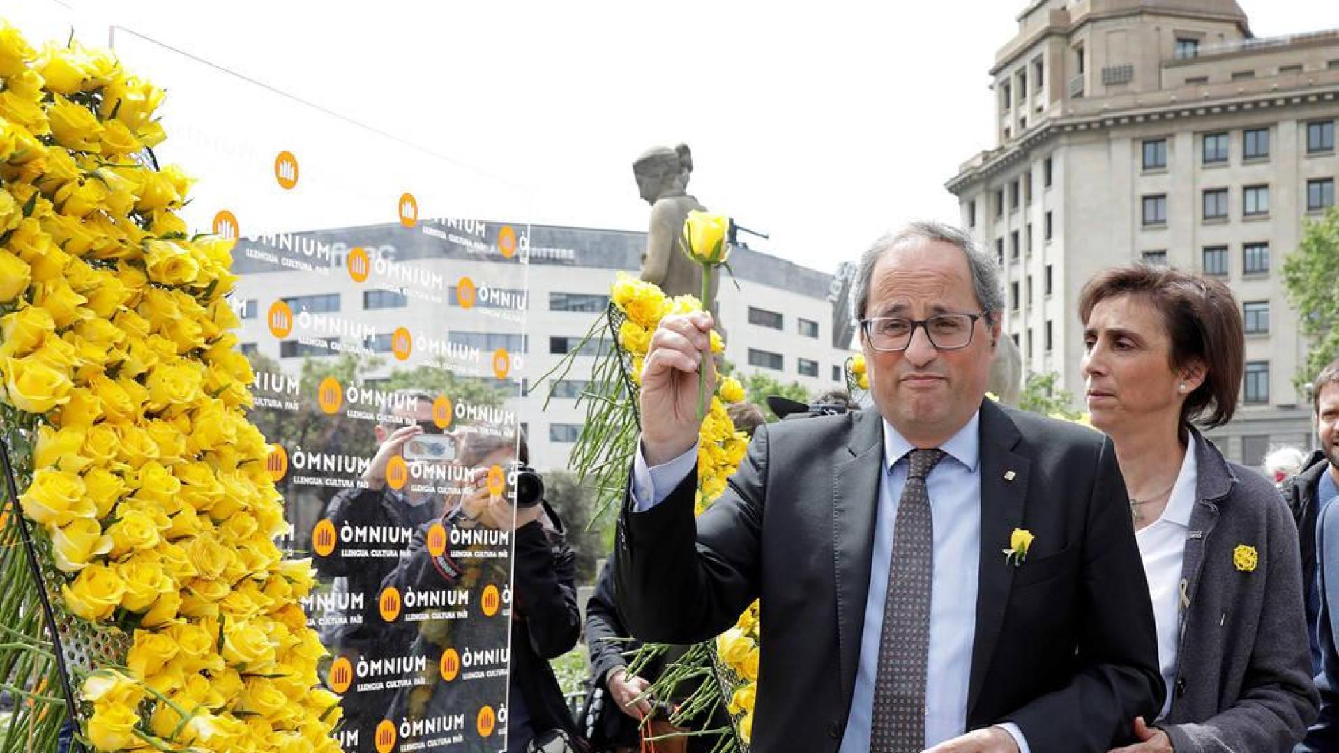 El presidente de la Generalitat, Quim Torra, coloca una rosa amarilla en el mural que recuerda a los independentistas presos instalado por Ómnium Cultural con motivo de la Diada de Sant Jordi.