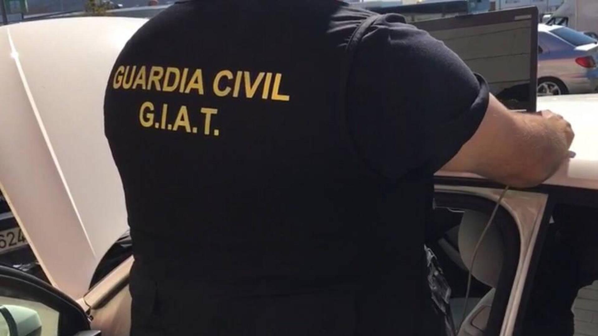 Un agente de la Guardia Civil, durante la operación, junto a uno de los vehículos.