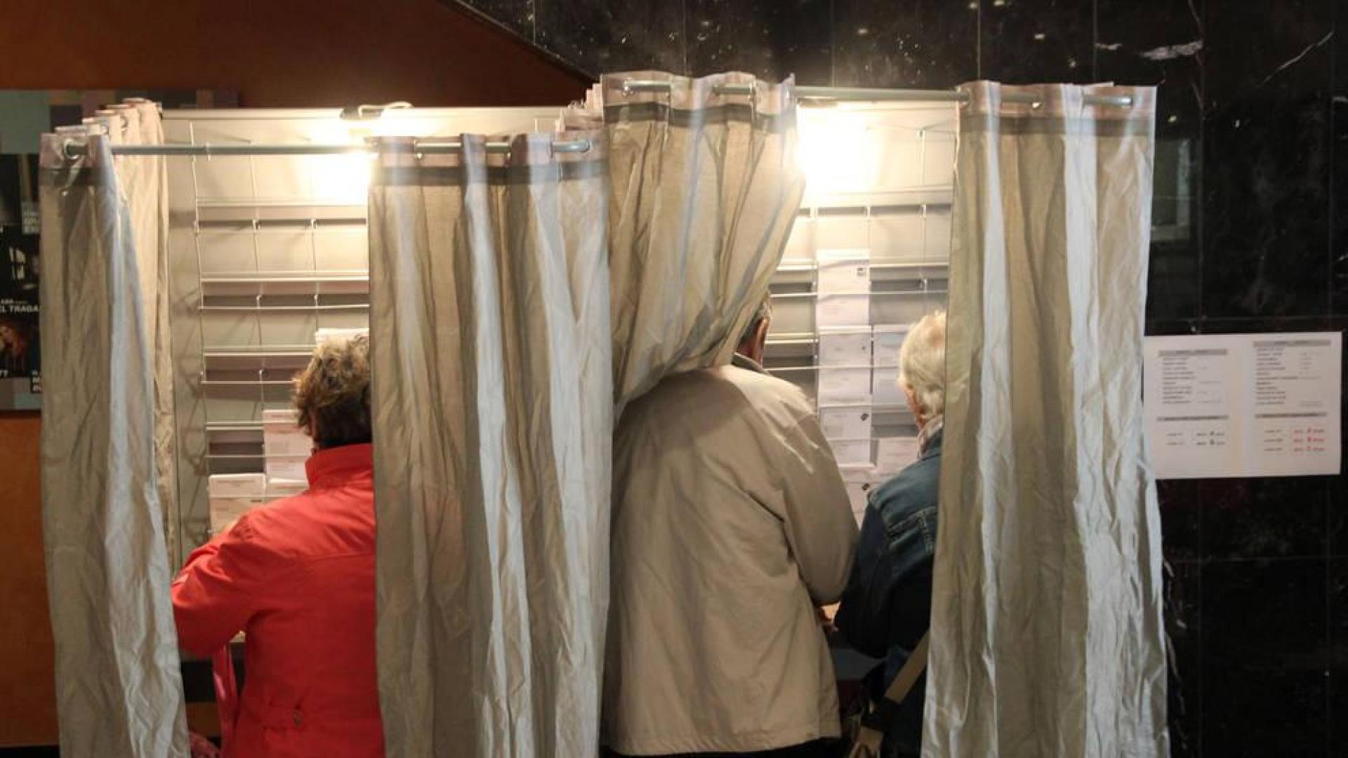 Dos personas preparan sus votos en una cabina durante las elecciones del 28A