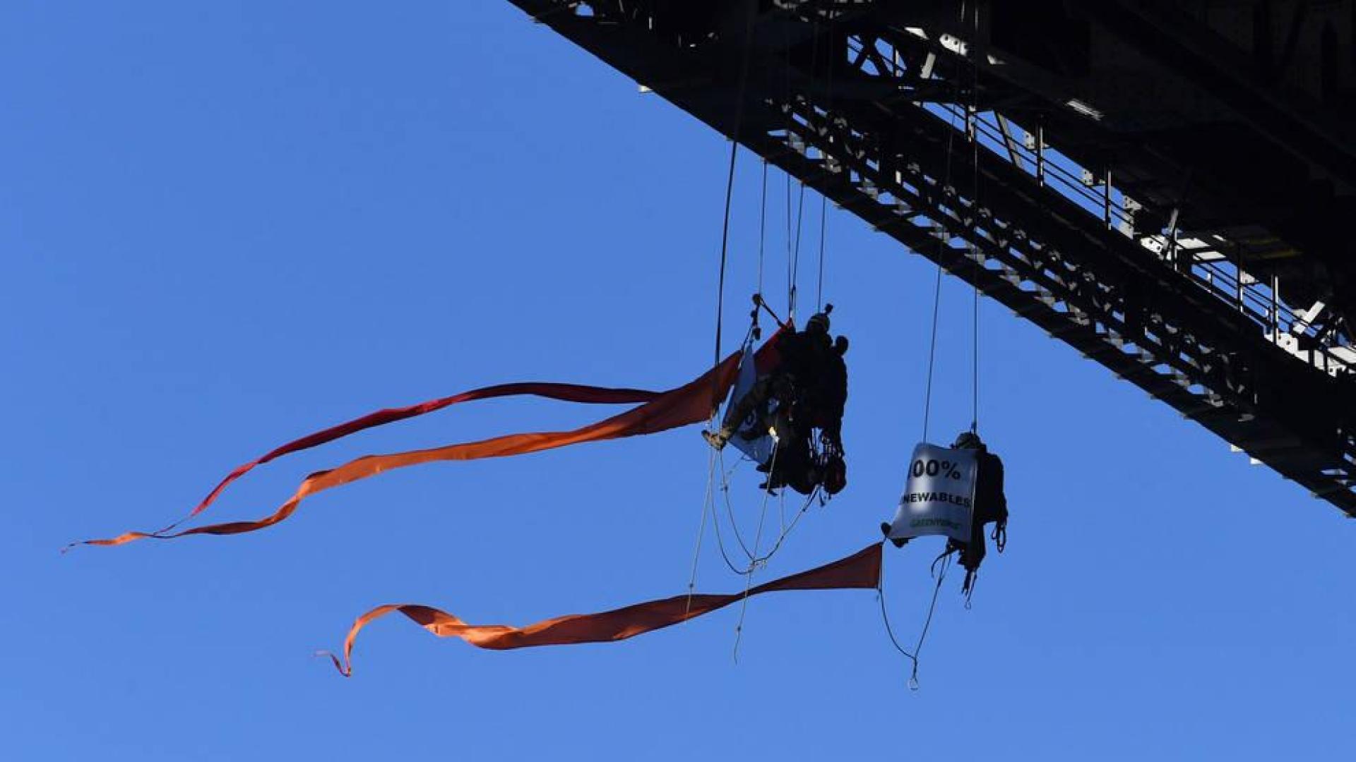 Activistas de la ONG Greenpeace cuelgan del puente en la bahía de Sídney durante una protesta