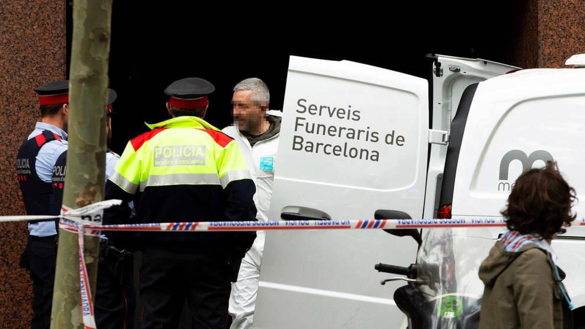 Mossos d'Esquadra y personal de los Servicios Funerarios retiran el cuerpo sin vida del hombre que ha fallecido tiroteado en la calle Comte d'Urgell, en el distrito del Eixample de Barcelona.