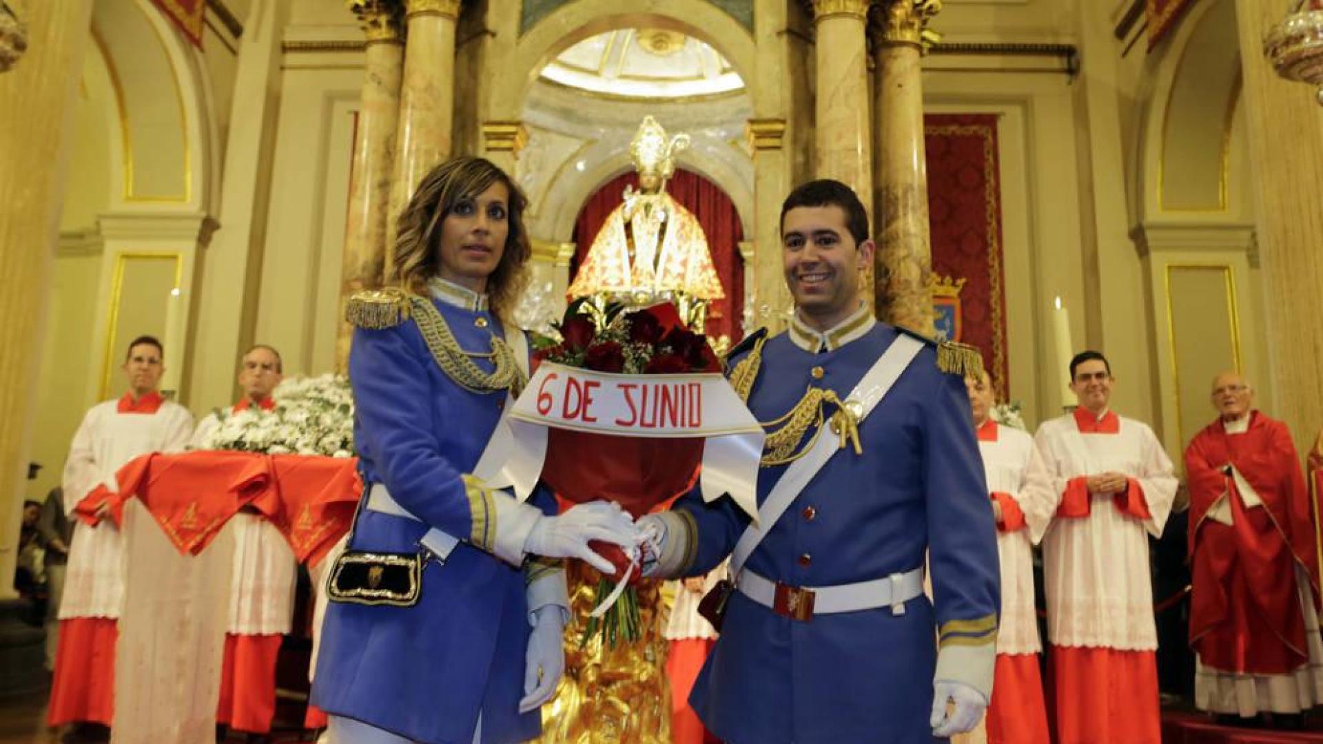Dos policías municipales, con el uniforme de gala, depositan un ramo de seis rosas ante la imagen de San Fermín.