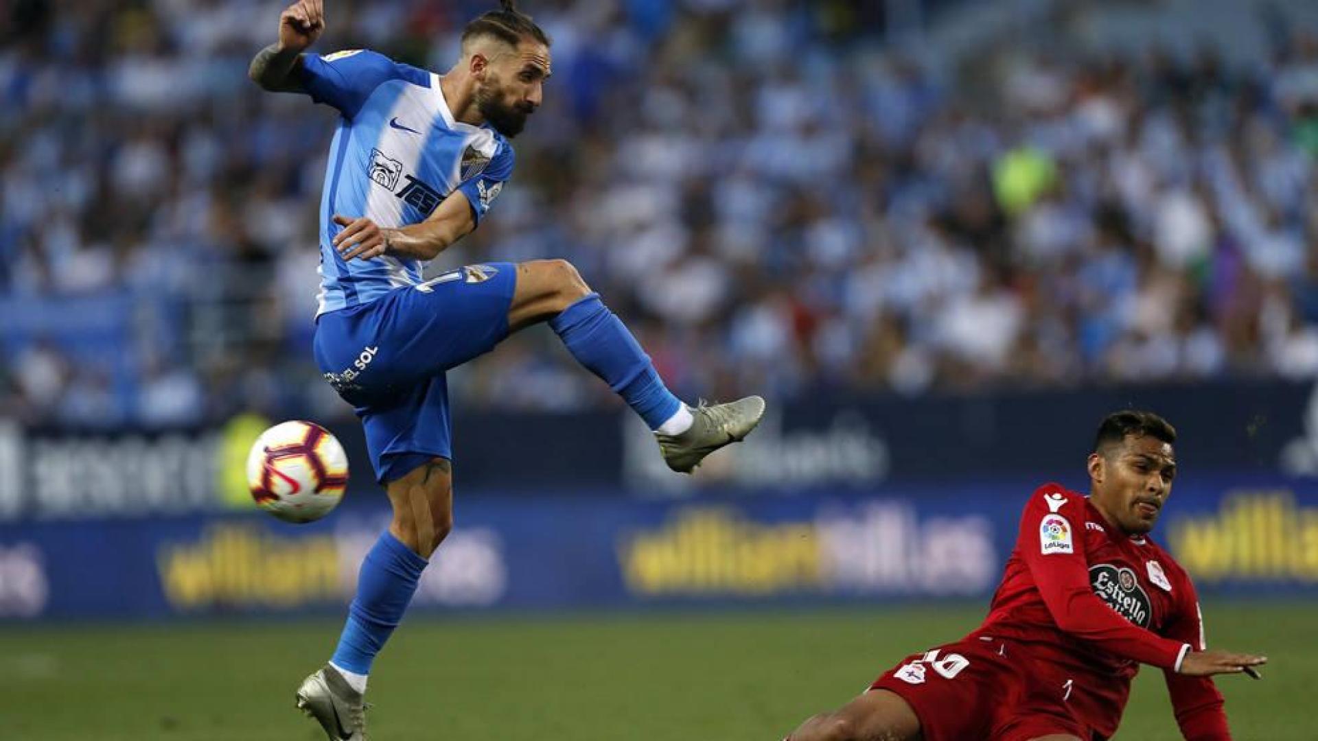 El defensa del Málaga Miguel Ángel Cifuentes chuta el balón ante el delantero argentino del Deportivo de La Coruña Matías Nahuel.