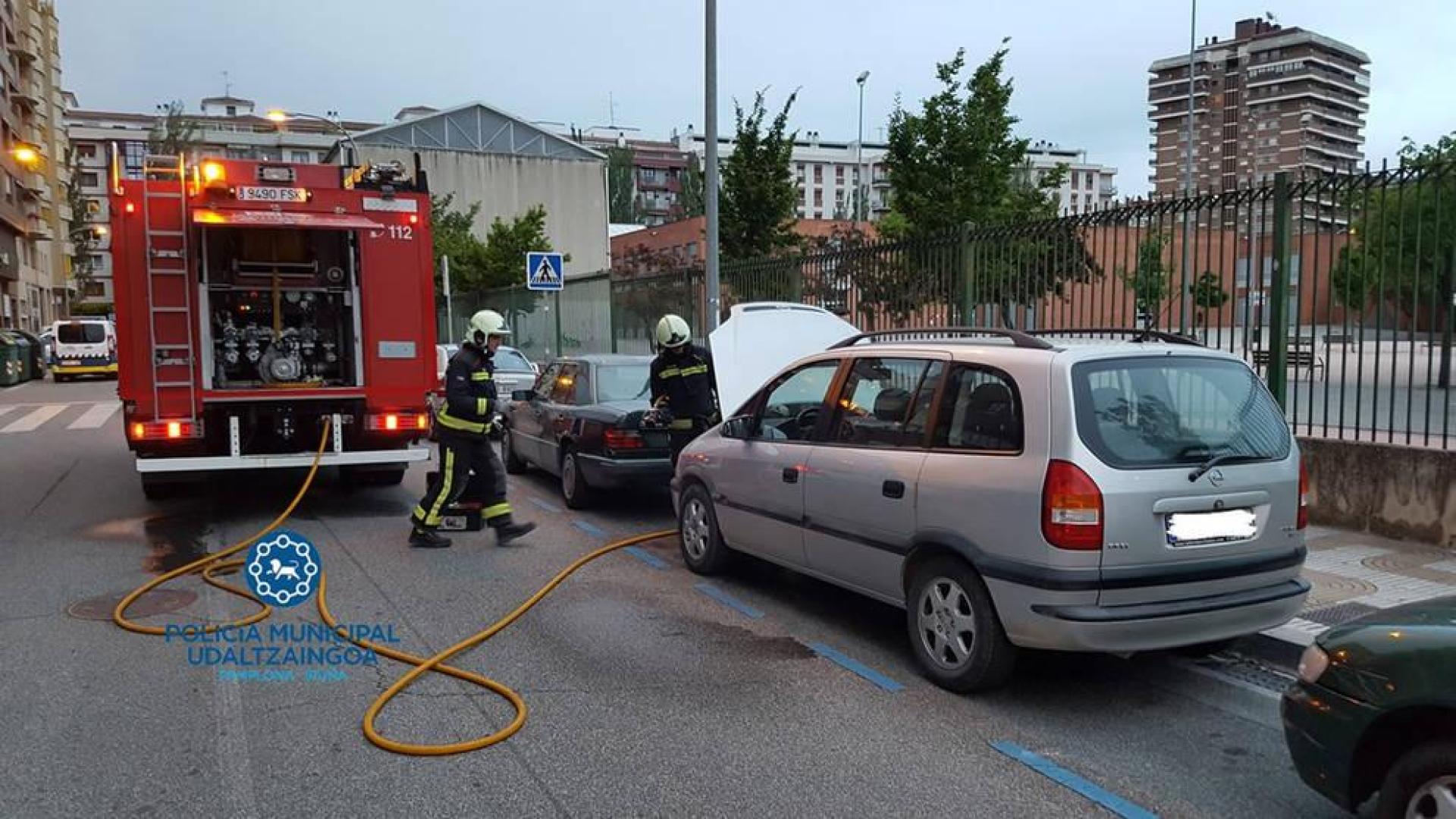 Los bomberos sofocan el fuego generado en un coche al arrancarlo, en la calle Pintor Maeztu.