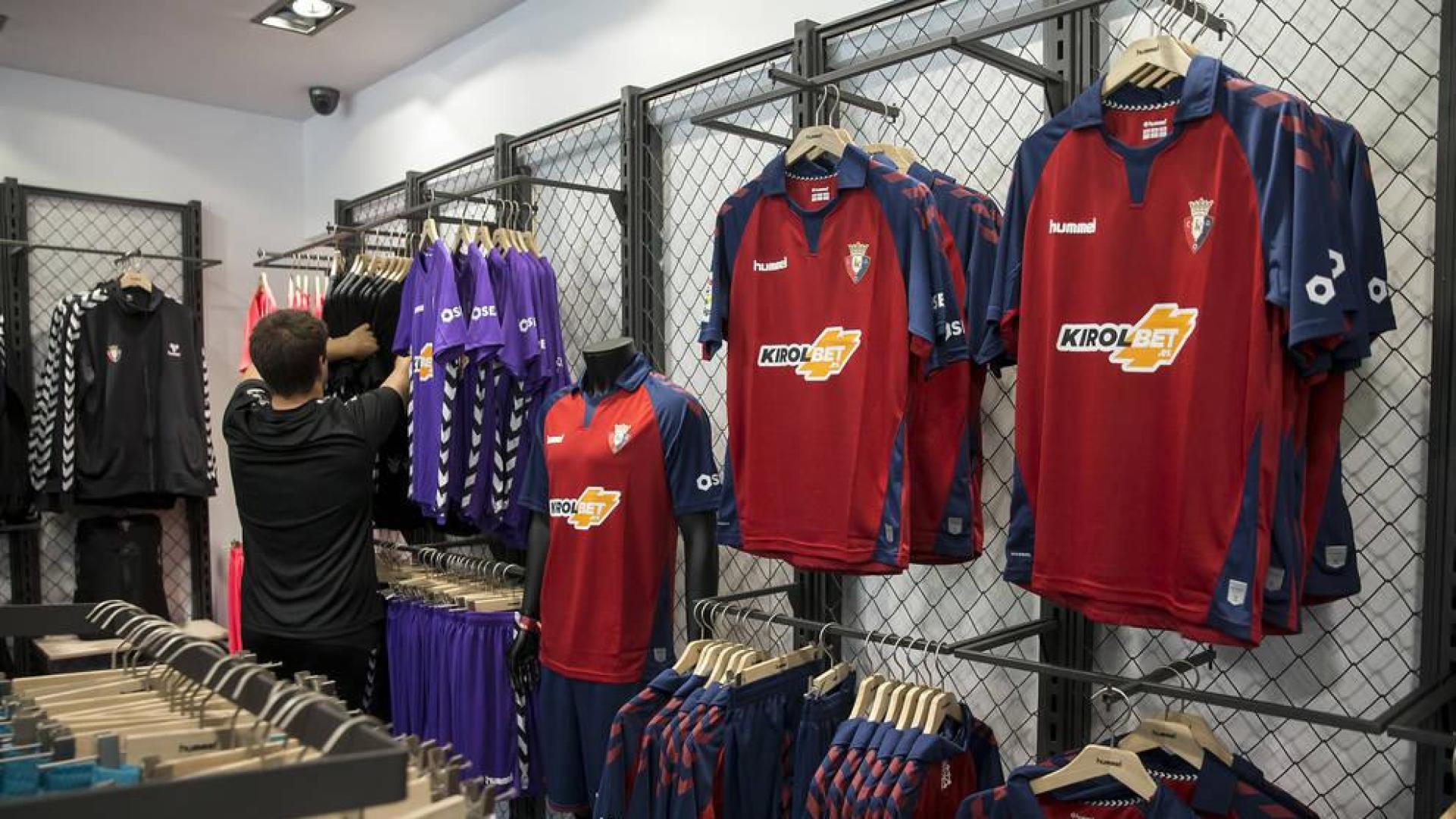 Un cliente supervisa las camisetas de portero. A la derecha, la primera equipación expuesta en la tienda del club de El Sadar.