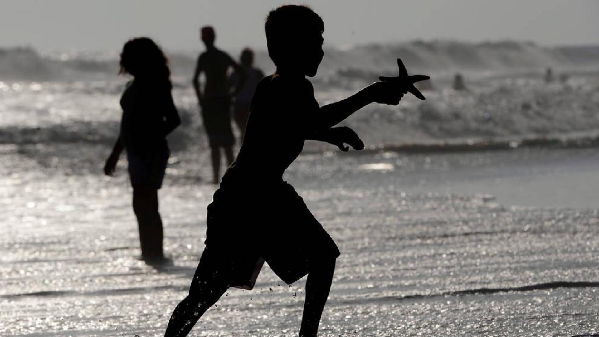 Varias personas se bañan en la playa de Huntington en California, Estados Unidos.
