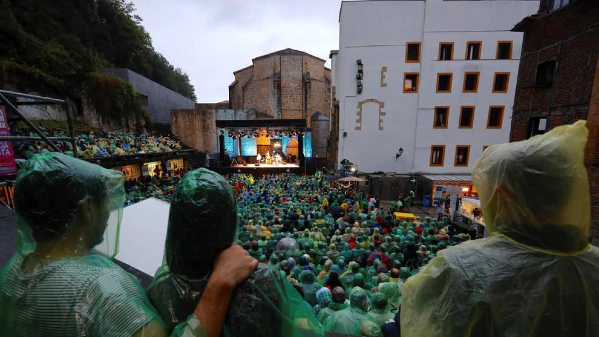 El público asiste, arropado con chubasqueros, al concierto del saxofonista Joshua Redman.