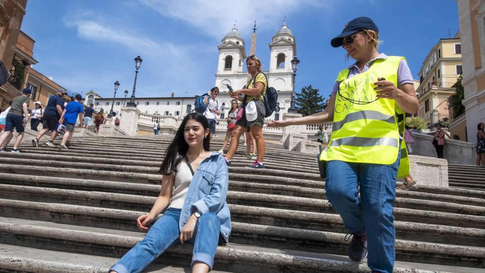 Una miembro de la Policía Municipal romana pide a una turista que no se siente en las escaleras de la Plaza de España.